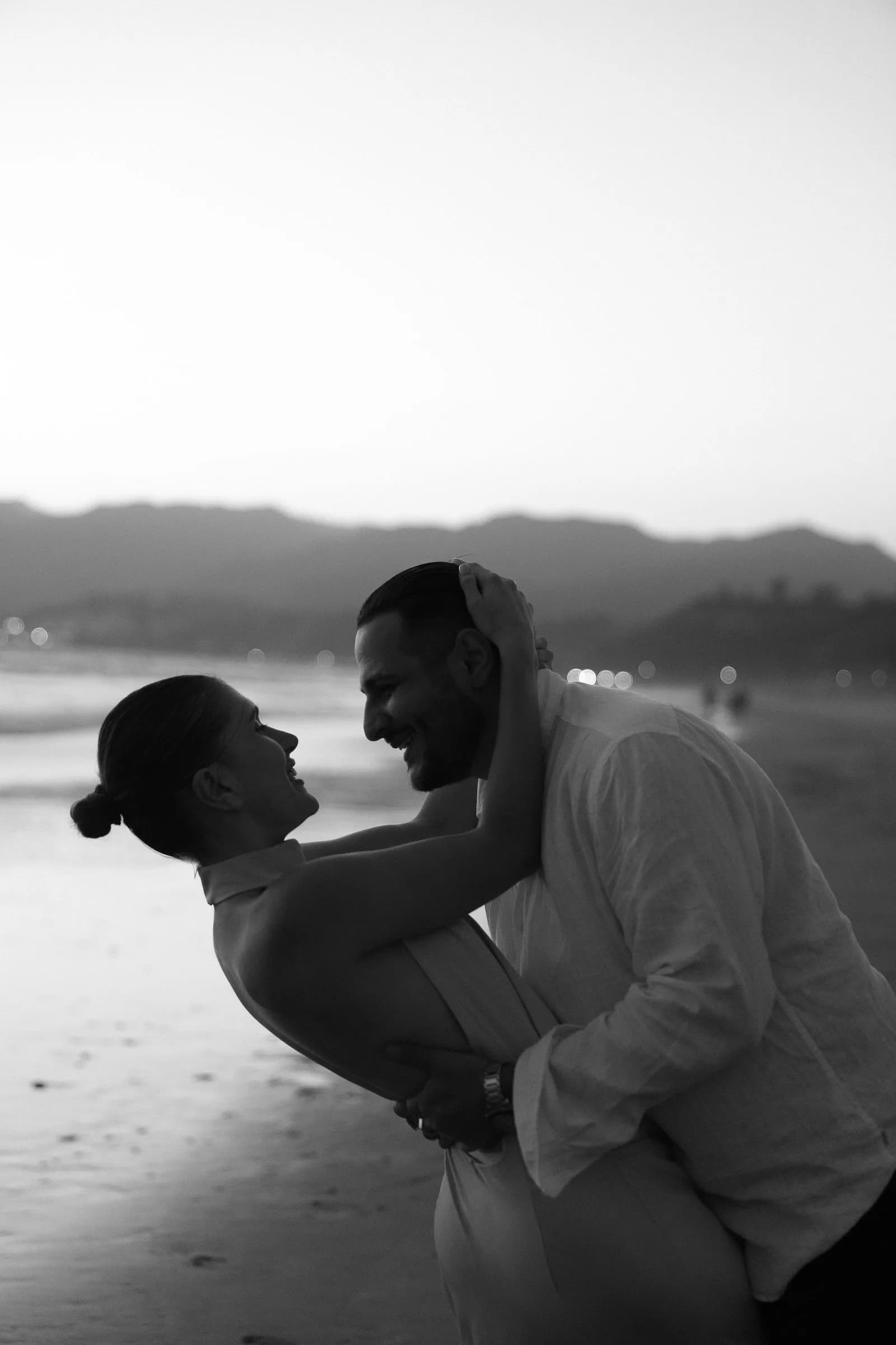 The couple laughing mid-embrace, photographed in black and white
