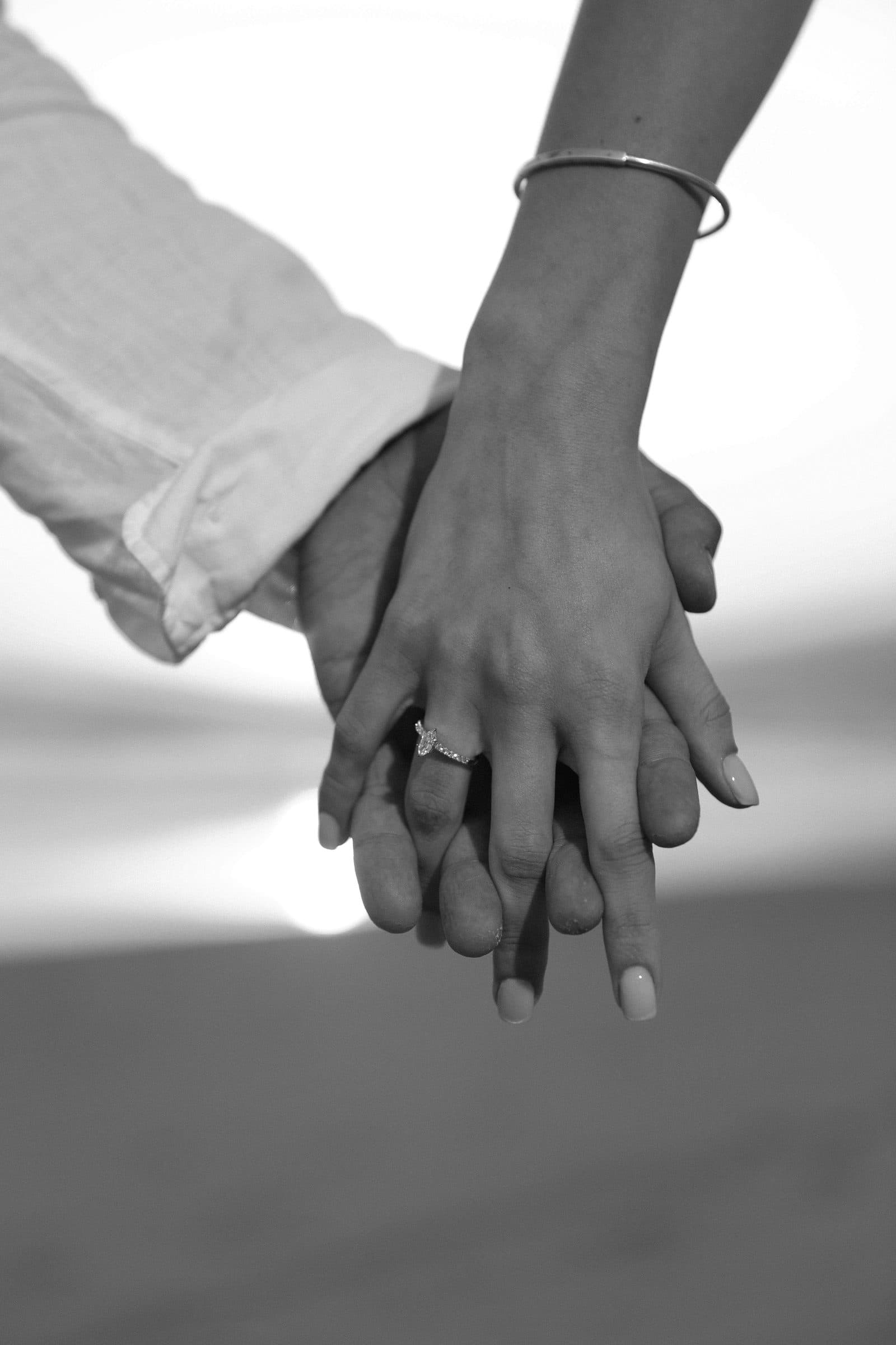 Two hands resting together, one wearing a wedding ring